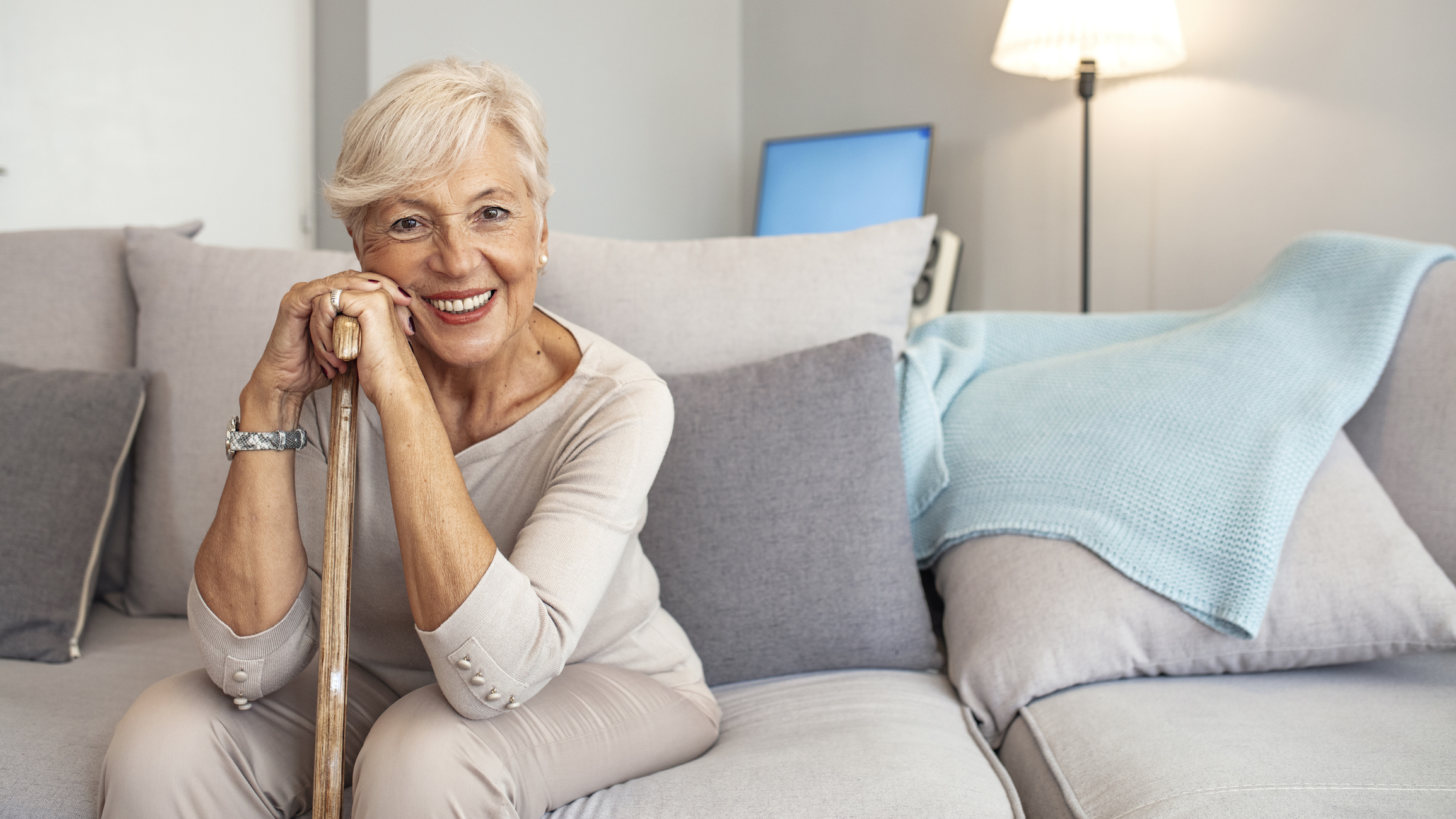 Happy senior woman with walking stick seating at home