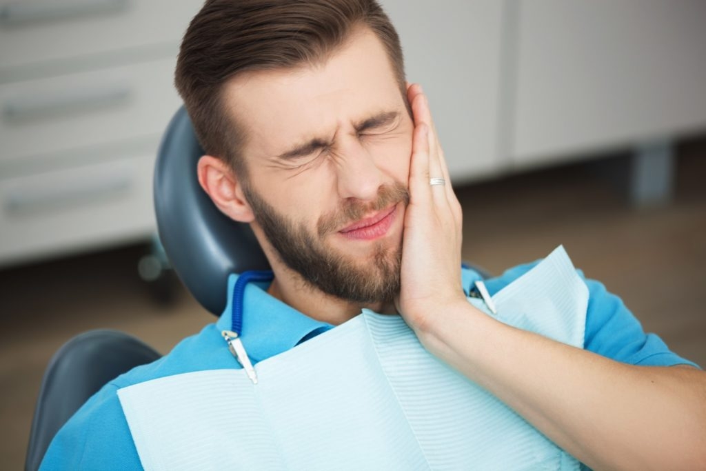 Young man with tooth pain sitting in a dentist's chair. Dental fear