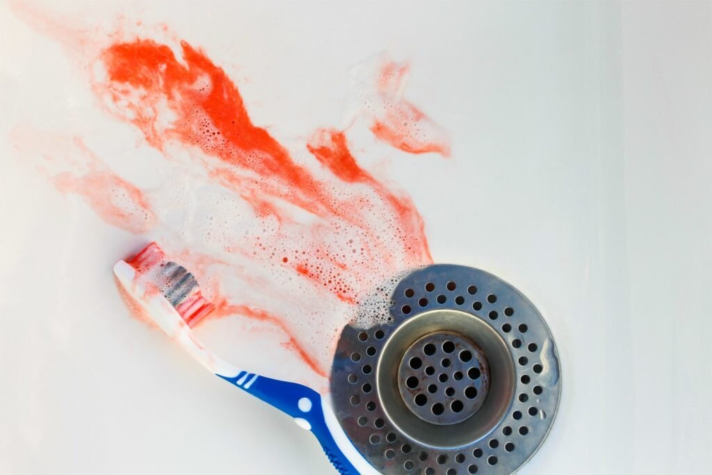 Blood on toothbrush on background of sink. Bleeding gums
